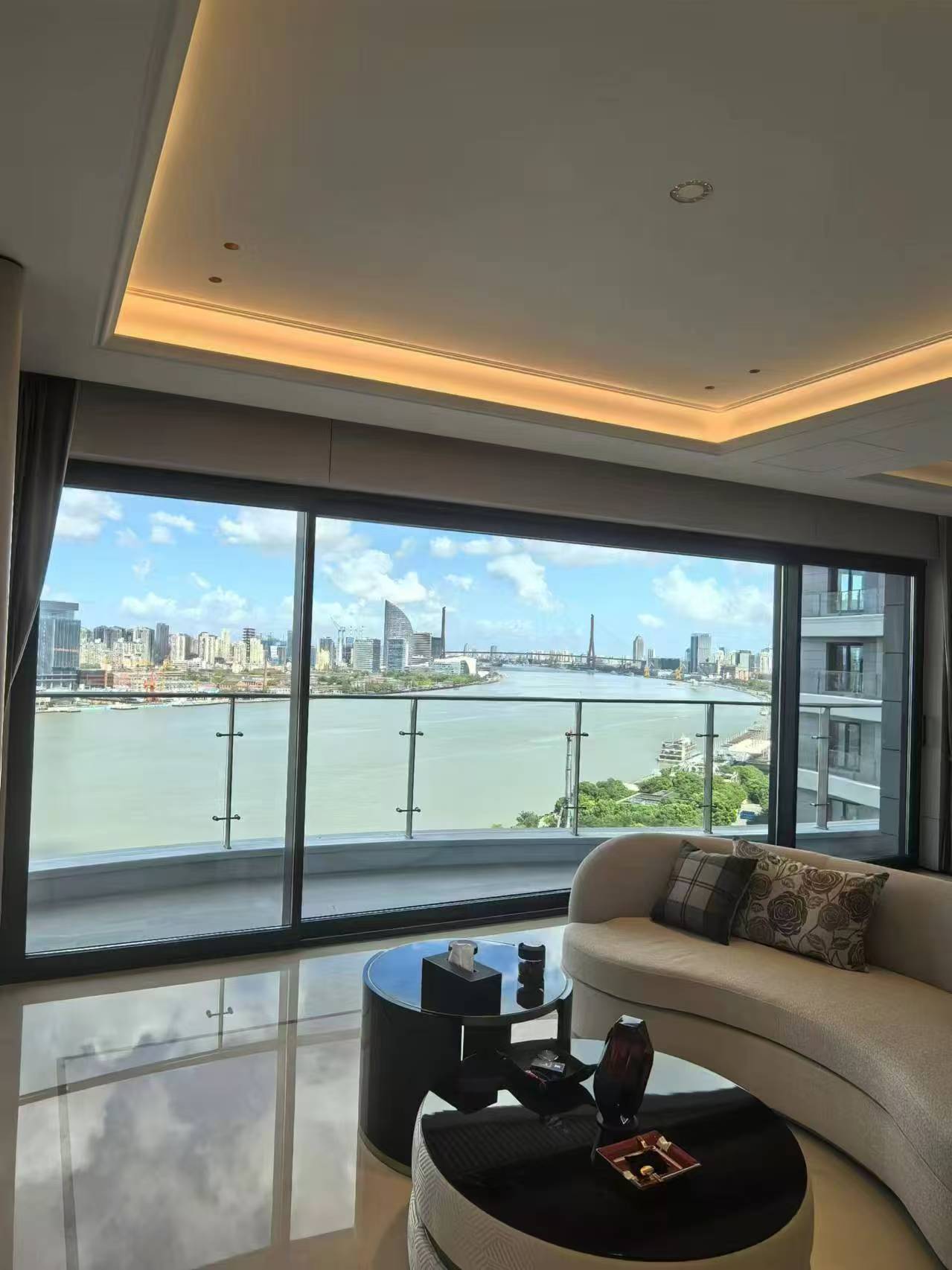 Supplier project photograph of dark-framed sliding glass doors opening onto a riverside apartment balcony
